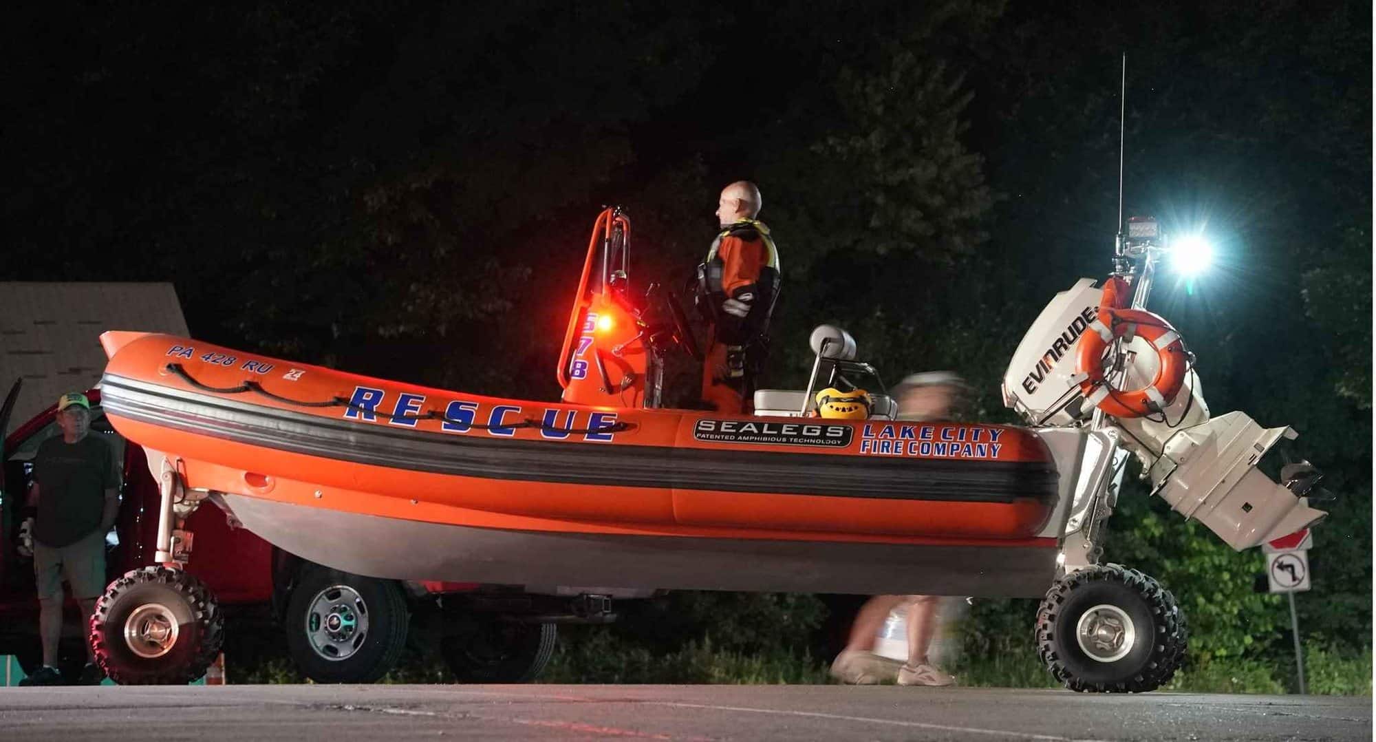 A Lake City Fire Company rescue Sealegs RIB standing on its wheels on a road at night, crew aboard under scene lighting