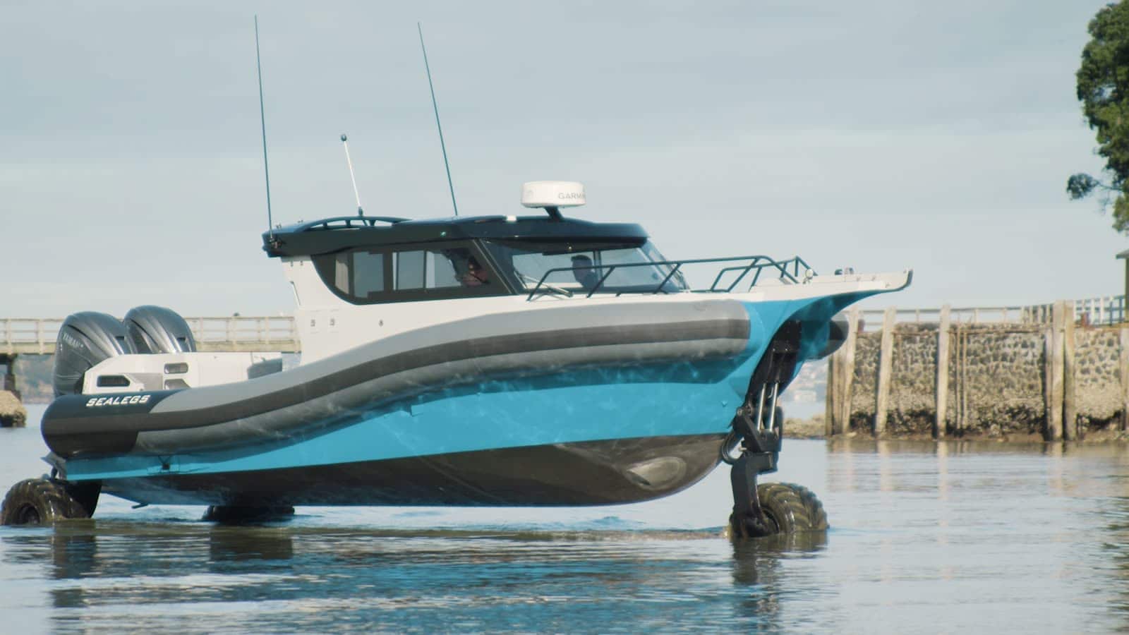 A Sealegs 12m cabin RIB driving out of the water onto the shore on its own wheels